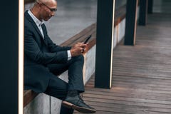 Homem de negócios que usa o telefone celular que senta-se fora imagem de stock Homem de negócios que usa o telefone celular que senta-se fora imagem de stock
