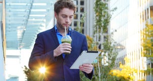 Homem de negócios que usa a tabuleta digital ao comer o suco video estoque Homem de negócios que usa a tabuleta digital ao comer o suco video estoque