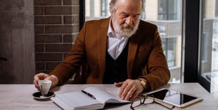 Homem de negócios velho de descanso chá masculino da bebida no local de trabalho foto de stock Homem de negócios velho de descanso chá masculino da bebida no local de trabalho foto de stock