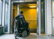 Homem deficiente na cadeira de rodas que vai no elevador imagem de stock royalty free Homem deficiente na cadeira de rodas que vai no elevador imagem de stock royalty free