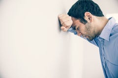 Homem deprimido que inclina sua cabeça contra uma parede Fotografia de Stock Royalty Free Homem deprimido que inclina sua cabeça contra uma parede Fotografia de Stock Royalty Free