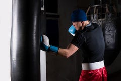 Homem desportivo novo em luvas de encaixotamento que treina com perfuração do encaixotamento imagens de stock royalty free Homem desportivo novo em luvas de encaixotamento que treina com perfuração do encaixotamento imagens de stock royalty free