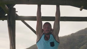 Homem do atleta que faz o exercício abdominal na barra transversal de madeira quando exercício exterior do gym Músculos de estôma vídeos de arquivo Homem do atleta que faz o exercício abdominal na barra transversal de madeira quando exercício exterior do gym Músculos de estôma vídeos de arquivo