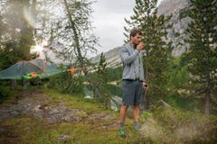 Homem ereto que bebe a barraca de suspensão próxima da bebida quente que acampa no lago com luz do sol Grupo de verão dos povos d fotos de stock royalty free Homem ereto que bebe a barraca de suspensão próxima da bebida quente que acampa no lago com luz do sol Grupo de verão dos povos d fotos de stock royalty free