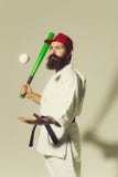 Homem farpado do karat? no quimono, tamp?o, bast?o de beisebol verde, bola imagem de stock Homem farpado do karat? no quimono, tamp?o, bast?o de beisebol verde, bola imagem de stock