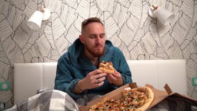 Homem farpado no roupão verde no quarto na cama para comer a pizza para apreciá-la movimento lento filme Homem farpado no roupão verde no quarto na cama para comer a pizza para apreciá-la movimento lento filme