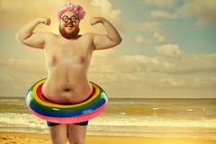 Homem gordo engraçado em um roupa de banho com um círculo inflável no bea Foto de Stock Royalty Free Homem gordo engraçado em um roupa de banho com um círculo inflável no bea Foto de Stock Royalty Free