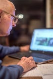 Homem idoso que usa um computador para verificar em linha seu dinheiro, Hampshire, Inglaterra, U K fotografia de stock royalty free Homem idoso que usa um computador para verificar em linha seu dinheiro, Hampshire, Inglaterra, U K fotografia de stock royalty free