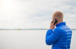 Homem louro que usa o telefone celular no lago imagens de stock Homem louro que usa o telefone celular no lago imagens de stock