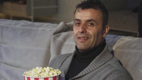 Homem maduro considerável que mostra os polegares acima ao sentar-se no cinema video estoque Homem maduro considerável que mostra os polegares acima ao sentar-se no cinema video estoque