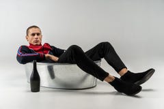 Homem modelo considerável com corte de cabelo curto no vestuário desportivo que senta-se no banho do metal foto de stock Homem modelo considerável com corte de cabelo curto no vestuário desportivo que senta-se no banho do metal foto de stock