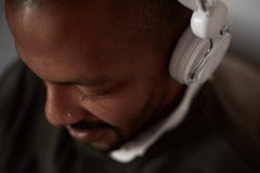 Homem negro africano feliz que escuta a música que relaxa no sofá do sofá com os fones de ouvido na sala de visitas da casa Retra imagens de stock royalty free Homem negro africano feliz que escuta a música que relaxa no sofá do sofá com os fones de ouvido na sala de visitas da casa Retra imagens de stock royalty free