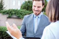 Homem novo bem sucedido e executivos fêmeas que encontram-se na frente de um prédio de escritórios, falando e discutindo imagem de stock Homem novo bem sucedido e executivos fêmeas que encontram-se na frente de um prédio de escritórios, falando e discutindo imagem de stock