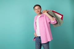 Homem novo bonito na camisa cor-de-rosa que guarda sacos shoping coloridos no ombro foto de stock royalty free Homem novo bonito na camisa cor-de-rosa que guarda sacos shoping coloridos no ombro foto de stock royalty free