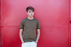 Homem novo considerável elegante com um penteado à moda em um t-shirt do verde do vintage na calças branca perto da parede cor-de fotos de stock Homem novo considerável elegante com um penteado à moda em um t-shirt do verde do vintage na calças branca perto da parede cor-de fotos de stock