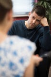 Homem novo deprimido que fala ao conselheiro imagem de stock Homem novo deprimido que fala ao conselheiro imagem de stock