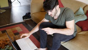 Homem novo em casa com o cartão de crédito para comprar em linha coisas imagens de stock royalty free Homem novo em casa com o cartão de crédito para comprar em linha coisas imagens de stock royalty free