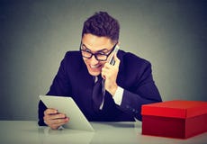 Homem novo entusiasmado que coloca a ordem em linha sobre o telefone usando o tablet pc fotos de stock Homem novo entusiasmado que coloca a ordem em linha sobre o telefone usando o tablet pc fotos de stock