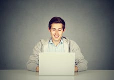 Homem novo feliz que trabalha no computador portátil imagem de stock Homem novo feliz que trabalha no computador portátil imagem de stock