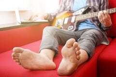 Homem novo ocasionalmente vestido com a guitarra que joga músicas na sala em casa Conceito em linha das lições da guitarra Pratic imagem de stock royalty free Homem novo ocasionalmente vestido com a guitarra que joga músicas na sala em casa Conceito em linha das lições da guitarra Pratic imagem de stock royalty free