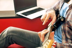 Homem novo ocasionalmente vestido com a guitarra que joga músicas na sala em casa Conceito em linha das lições da guitarra Pratic foto de stock Homem novo ocasionalmente vestido com a guitarra que joga músicas na sala em casa Conceito em linha das lições da guitarra Pratic foto de stock