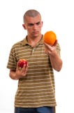 Homem novo que compara a laranja à maçã foto de stock Homem novo que compara a laranja à maçã foto de stock