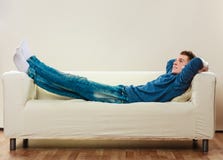 Homem novo que relaxa no sofá Fotos de Stock Royalty Free Homem novo que relaxa no sofá Fotos de Stock Royalty Free