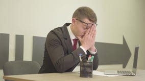 Homem ocupado forçado nervoso novo do retrato no vestuário formal e nos vidros que sentam-se no escritório na frente do portátil filme Homem ocupado forçado nervoso novo do retrato no vestuário formal e nos vidros que sentam-se no escritório na frente do portátil filme