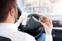 Homem que comem o café da manhã e condução assentada no carro foto de stock Homem que comem o café da manhã e condução assentada no carro foto de stock