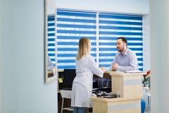 Homem que fala ao recepcionista fêmea no hospital imagens de stock Homem que fala ao recepcionista fêmea no hospital imagens de stock