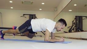 Homem que faz a prancha dinâmica no gym Posicione a prancha sobre o assoalho com cotovelos e dedos do pé video estoque Homem que faz a prancha dinâmica no gym Posicione a prancha sobre o assoalho com cotovelos e dedos do pé video estoque