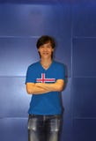 Homem que veste a camisa do teste padr?o da bandeira de Isl?ndia e para cruzar seu bra?o no fundo azul da parede fotos de stock royalty free Homem que veste a camisa do teste padr?o da bandeira de Isl?ndia e para cruzar seu bra?o no fundo azul da parede fotos de stock royalty free