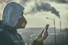 Homem que veste uma máscara protetora contra a névoa real e que verifica a poluição do ar atual com o app esperto do telefone imagem de stock royalty free Homem que veste uma máscara protetora contra a névoa real e que verifica a poluição do ar atual com o app esperto do telefone imagem de stock royalty free