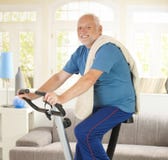 Homem sênior que sorri na bicicleta da aptidão foto de stock Homem sênior que sorri na bicicleta da aptidão foto de stock