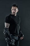 Homem Tattooed no tshirt e no casaco de cabedal Tatuagem farpada da mostra do homem no braço forte Forma macho com a barba em não imagens de stock Homem Tattooed no tshirt e no casaco de cabedal Tatuagem farpada da mostra do homem no braço forte Forma macho com a barba em não imagens de stock