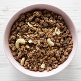 Homemade chocolate granola with nuts in a pink bowl over white wooden surface, top view. From above, overhead stock photos Homemade chocolate granola with nuts in a pink bowl over white wooden surface, top view. From above, overhead stock photos