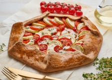 Homemade galette with vegetables, wholegrain pie with tomatoes, zucchini, cheese. Side view, close up. Light white wooden table royalty free stock photography Homemade galette with vegetables, wholegrain pie with tomatoes, zucchini, cheese. Side view, close up. Light white wooden table royalty free stock photography