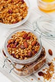 Homemade granola in jar on white table, healthy breakfast of oatmeal muesli, nuts, seeds and dried fruit stock photography Homemade granola in jar on white table, healthy breakfast of oatmeal muesli, nuts, seeds and dried fruit stock photography