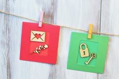 Composition of greeting cards hanging on jute cord. Vintage letter and rose on red paper background, lock and key on green stock photography Composition of greeting cards hanging on jute cord. Vintage letter and rose on red paper background, lock and key on green stock photography