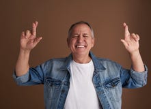Homme adulte drôle croisant ses doigts tout en se tenant avec les yeux fermés image stock Homme adulte drôle croisant ses doigts tout en se tenant avec les yeux fermés image stock