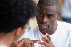 Homme africain focalisé ayant l'entretien sérieux avec la femme à se réunir image libre de droits Homme africain focalisé ayant l'entretien sérieux avec la femme à se réunir image libre de droits