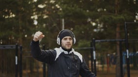 Homme bel dans des écouteurs faisant l'exercice d'échauffement tandis que musique de écoute en parc d'hiver banque de vidéos Homme bel dans des écouteurs faisant l'exercice d'échauffement tandis que musique de écoute en parc d'hiver banque de vidéos