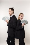 Homme bel des deux employés et belle femme blonde dans les costumes noirs se tenant de nouveau au dos avec l'argent dans des main image libre de droits Homme bel des deux employés et belle femme blonde dans les costumes noirs se tenant de nouveau au dos avec l'argent dans des main image libre de droits