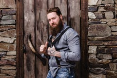 Homme brutal fort avec une barbe et tatouages sur ses mains habill?es dans des poses ?l?gantes de v?tements sport sur le fond de images stock Homme brutal fort avec une barbe et tatouages sur ses mains habill?es dans des poses ?l?gantes de v?tements sport sur le fond de images stock