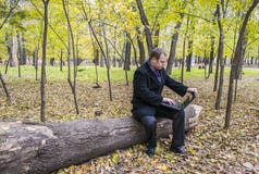 Homme d'affaires ayant un ordinateur portable dans le parc en automne Un homme travaille à un ordinateur en parc photographie stock Homme d'affaires ayant un ordinateur portable dans le parc en automne Un homme travaille à un ordinateur en parc photographie stock