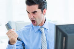 Homme d'affaires criant comme il donne le téléphone au bureau Photographie stock Homme d'affaires criant comme il donne le téléphone au bureau Photographie stock