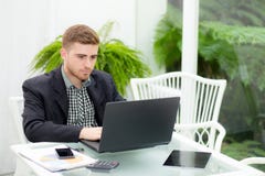 homme d'affaires et sourire, comme il travaillent sur son ordinateur portable dans le salon Images libres de droits homme d'affaires et sourire, comme il travaillent sur son ordinateur portable dans le salon Images libres de droits