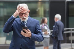 Homme d'affaires supérieur inquiété recevant la mauvaise nouvelle des associés, tenant sa tête photo libre de droits Homme d'affaires supérieur inquiété recevant la mauvaise nouvelle des associés, tenant sa tête photo libre de droits
