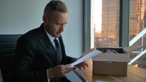 Homme d'affaires sûr dans le costume formel avec la boîte mobile dans le bureau déballant des articles Homme d'affaires sûr dans le costume formel avec la boîte mobile dans le bureau déballant des articles
