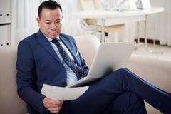 Homme d'affaires travaillant avec le contrat et l'ordinateur portable au bureau image stock Homme d'affaires travaillant avec le contrat et l'ordinateur portable au bureau image stock